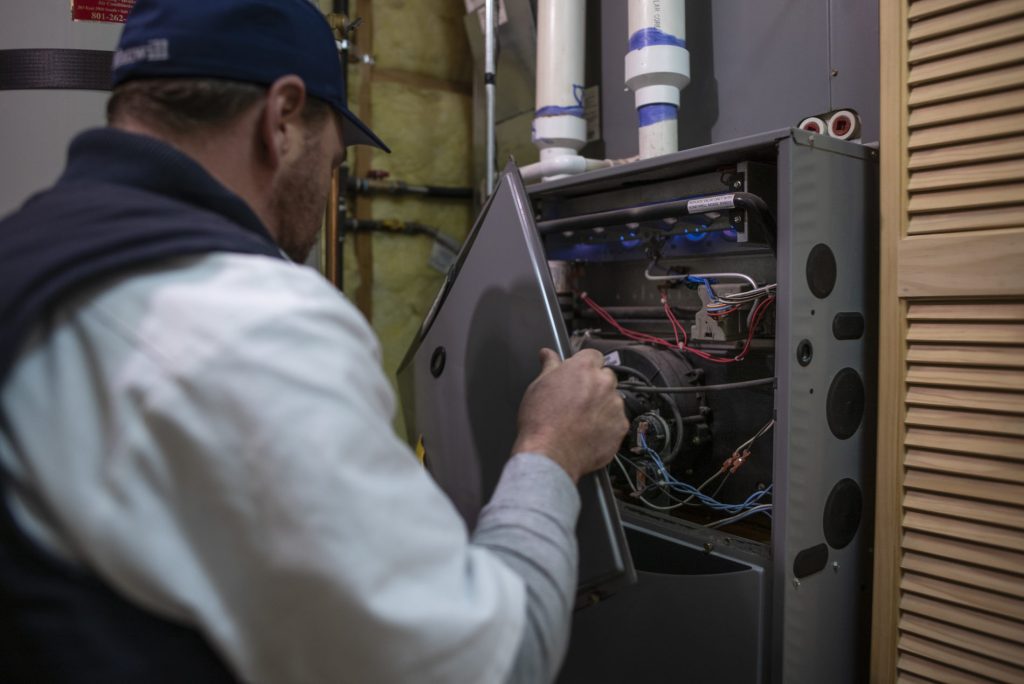 HVAC technician opening a residential furnace to inspect internal components.