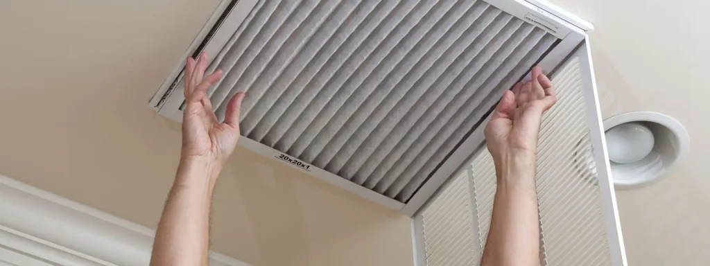 Person replacing a ceiling-mounted HVAC air filter, highlighting the importance of routine maintenance for better air quality and system efficiency.